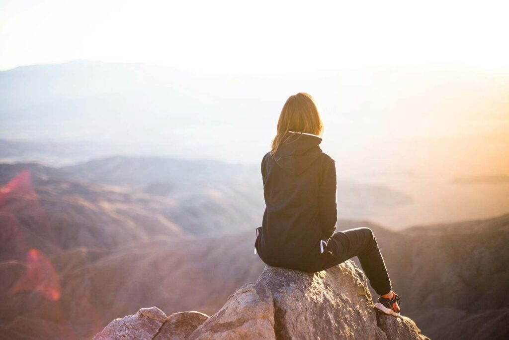 woman sitting on rock overlooking the mountain range